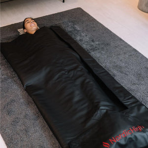 Kvinna som ligger i en filt för infraröd bastu - Pro
